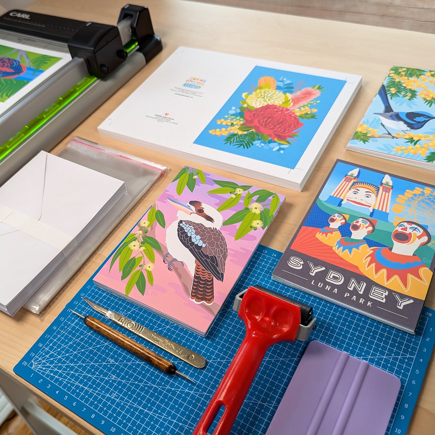 Work table showing Australiana greeting cards by Sarah Epstein Studio alongside card making equipment.