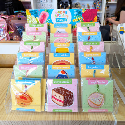 Display stand showing various kawaii keychain and sticker designs by Sarah Epstein Studio.